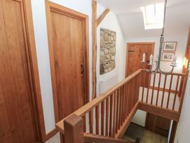 A stairway landing area with wooden doors a stone wall section and a chandelier at 5 Cart-Tws Bach in St Davids