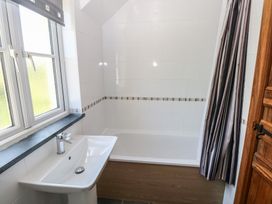 A bathroom with a bathtub a sink a window with a blind and a wooden door at 5 Cart-Tws Bach in St Davids