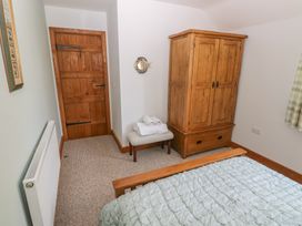 A bedroom with a wooden wardrobe a wooden door a bench with towels and a bed with a quilt at 5 Cart-Tws Bach in St Davids