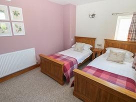 A bedroom with two single wooden beds and pink checkered blankets at 5 Cart-Tws Bach in St Davids