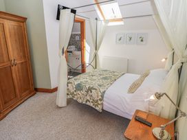 A bedroom with a canopy bed a wooden wardrobe a bedside table lamp and an open door to a bathroom at 5 Cart-Tws Bach in St Davids