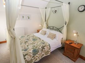 A bedroom with a four poster bed two nightstands and wall clock at 5 Cart-Tws Bach in St Davids