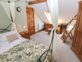 A bedroom with a bed bedside table wooden door wooden dresser chair full length mirror and wardrobe at 5 Cart-Tws Bach in St Davids