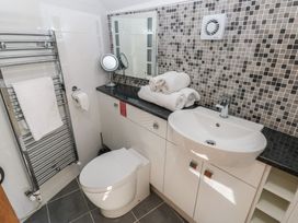 A bathroom with a toilet a sink with countertop rolled towels a mirror and a towel rack at 5 Cart-Tws Bach in St Davids