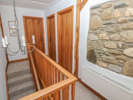 A hallway with wooden doors a wooden handrail a stone feature wall and a chandelier at 5 Cart-Tws Bach in St Davids