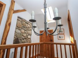 A hallway with wooden railing a stone wall section a wooden door a skylight and a ceiling light fixture at 5 Cart-Tws Bach in St Davids
