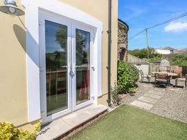 A white framed glass door leading outside to a garden with a gravel pathway and outdoor seating at 5 Cart-Tws Bach in St Davids
