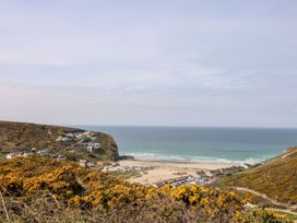 A view of a beach and ocean with houses on the cliff at The Old Piggery Porthtowan, Near St Agnes