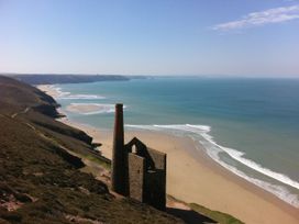 A coastal view with a chimney ruin on a cliff near the beach at The Old Piggery in Porthtowan, Near St Agnes