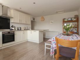 A kitchen with cabinets and a dining table at St Gregory’s Cottage in Oswaldkirk near Helmsley