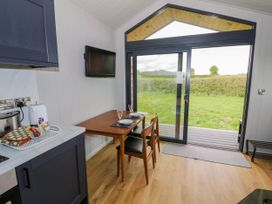 A dining area with a wooden table and two chairs near sliding glass doors overlooking a grassy field at Elmside Lodge in Welland Malvern