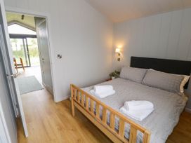 A bedroom with a wooden bed with gray bedding and two folded white towels on top at Elmside Lodge in Welland Malvern