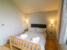 A bedroom with a bed with gray bedding and two rolled white towels on top at Elmside Lodge in Welland Malvern