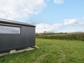 A small corrugated metal building next to a grassy field with hedges and hills in the background at Elmside Lodge in Welland Malvern