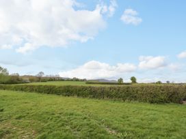 A grassy field with hedges and distant trees under a partly cloudy sky at Elmside Lodge in Welland Malvern