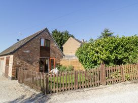 A brick house with a wooden picket fence and green bushes at Little Barn in Dodwell near Stratford-Upon-Avon