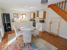 A kitchen and dining area with a round glass table and four chairs on a multicolored rug at Little Barn in Dodwell near Stratford-Upon-Avon