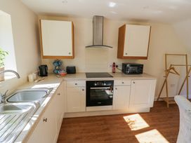 A kitchen with white cabinets a sink a stove a microwave and a wooden clothes rack at Little Barn in Dodwell near Stratford-Upon-Avon