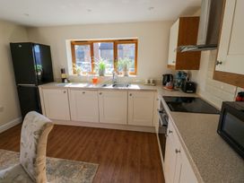 A kitchen with white cabinets a black refrigerator plants on the window ledge and kitchen appliances at Little Barn Dodwell near Stratford-Upon-Avon