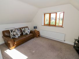 A sitting room with a brown leather sofa cushions side tables lamp a window and carpeted floor at Little Barn Dodwell near Stratford-Upon-Avon