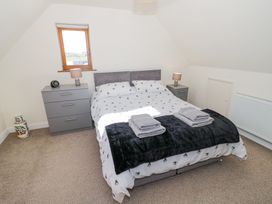 A bedroom with a double bed two bedside tables with lamps a chest of drawers and a small window at Little Barn Dodwell near Stratford-Upon-Avon