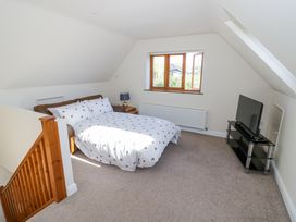 A bedroom with a double bed a side table with a lamp a window a television on a stand and a wooden staircase at Little Barn Dodwell near Stratford-Upon-Avon