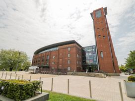 A large brick building with a tall tower and glass entrance of the Royal Shakespeare Company