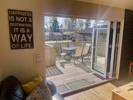 A living room with bifold doors leading to a deck at Woodburn Lodge in Otterburn