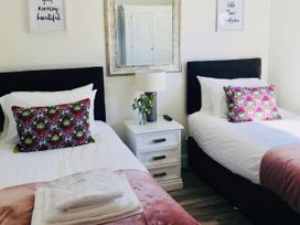 A bedroom with two beds and a nightstand at Woodburn Lodge in Otterburn