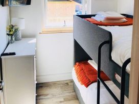 A bedroom with a bunk bed and dresser at Woodburn Lodge in Otterburn