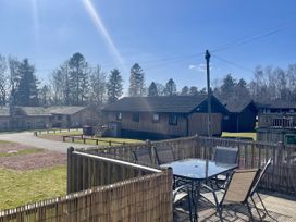 An outdoor area with cabins and a table with chairs at Woodburn Lodge in Otterburn