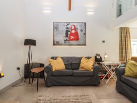 A living room with a dark sofa with yellow pillows a floor lamp and a side table at Puddaven Barn North Bovey near Chagford