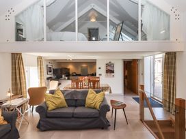 A living room with sofas and chairs overlooking a dining table and kitchen at Puddaven Barn in North Bovey near Chagford