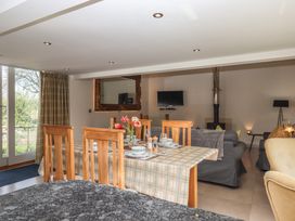 A dining table with plates and flowers next to a living room with sofas and a television at Puddaven Barn in North Bovey near Chagford