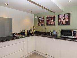 A kitchen with white cabinets a black countertop a microwave kettle coffee machine and three paintings on the wall at Puddaven Barn in North Bovey near Chagford