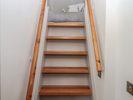 A staircase with wooden steps and handrails leading to a landing with a chair at Puddaven Barn in North Bovey near Chagford