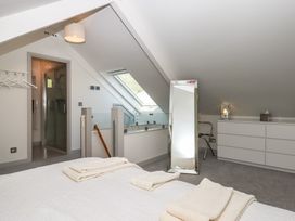 A bedroom with a bed, folded towels, a full-length mirror, a dresser, a chair, and a skylight window at Puddaven Barn North Bovey near Chagford