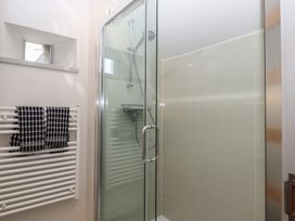 A shower with glass doors and a towel rack with two towels in a bathroom at Puddaven Barn North Bovey near Chagford