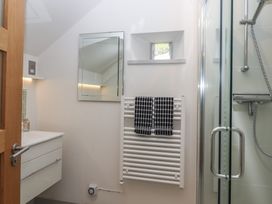 A bathroom with a shower enclosed by glass doors a white radiator with two black and white towels a mirror above a white vanity unit at Puddaven Barn in North Bovey near Chagford