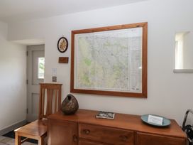 A wooden dresser with a sculptural object and a book below a framed map on a white wall with a wooden chair beside the dresser at Puddaven Barn North Bovey near Chagford