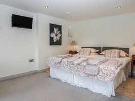 A bedroom with two beds side by side with patterned bedding towels and pillows a wall-mounted television and a floral painting at Puddaven Barn North Bovey near Chagford