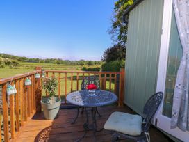A wooden deck with a metal table and two chairs overlooking a green field at Songbirds in St Michaels Kent