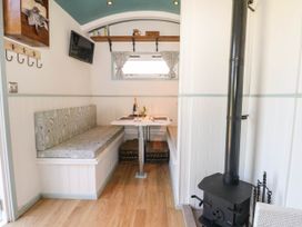 A small dining area with a table and bench seating near a wood stove in a compact room