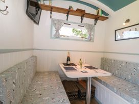 A small dining area with a white table and cushioned bench seating on both sides at Songbirds in St Michaels Kent