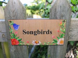A wooden fence with a sign that says Songbirds surrounded by flowers at Songbirds in St Michaels Kent