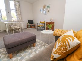 A living room with a sofa cushion plant ottoman table and chairs at Penzance Apartment in Penzance