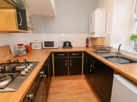 A kitchen with black cabinets wooden countertops a gas stove a sink a toaster a microwave and a bread container at Penzance Apartment in Penzance