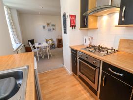 A kitchen with gas stove and oven and a small dining area with table and chairs at Penzance Apartment in Penzance
