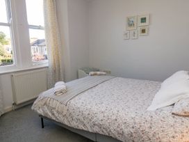 A bedroom with a bed covered in floral bedding and folded towels on the bed at Penzance Apartment in Penzance