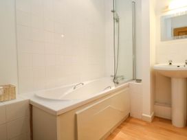 A bathroom with a bathtub shower combination and a pedestal sink at Penzance Apartment in Penzance